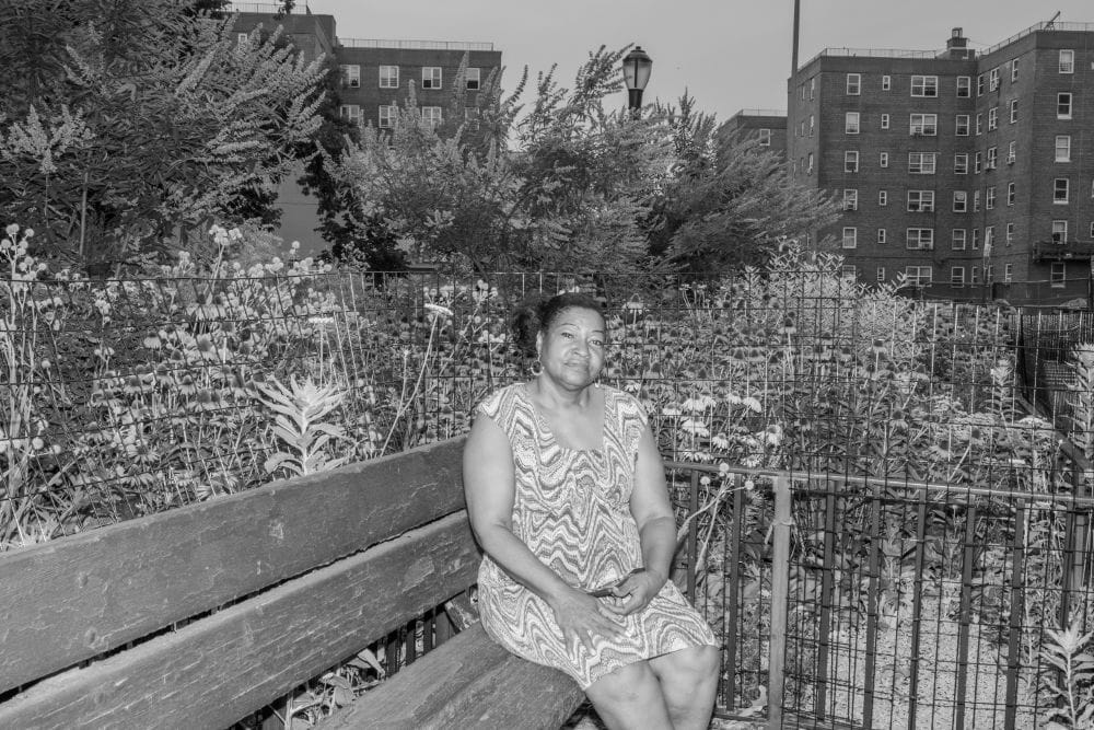Karen Blondel seated on a bench in front of a garden